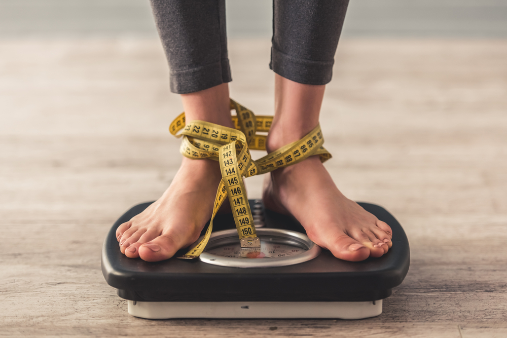 une femme se tient sur une balance avec un metre autour des pieds